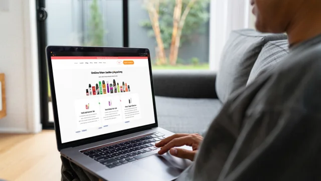 A person shopping for vapes online using a laptop in a comfortable home setting.